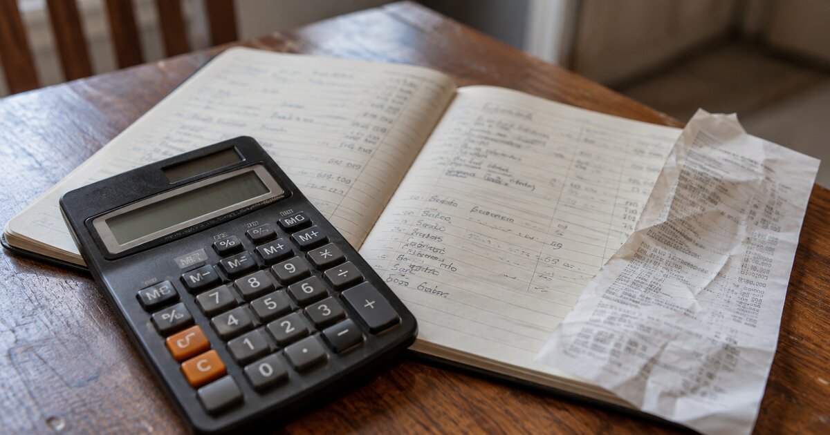 A calculator and shopping receipt on an open household notebook.
