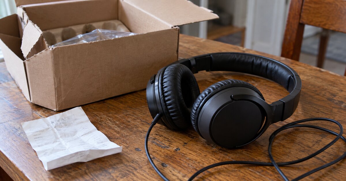 Headphones, opened packaging and a folded receipt on a table.