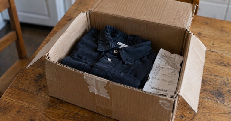 A folded shirt and receipt inside an open return box.