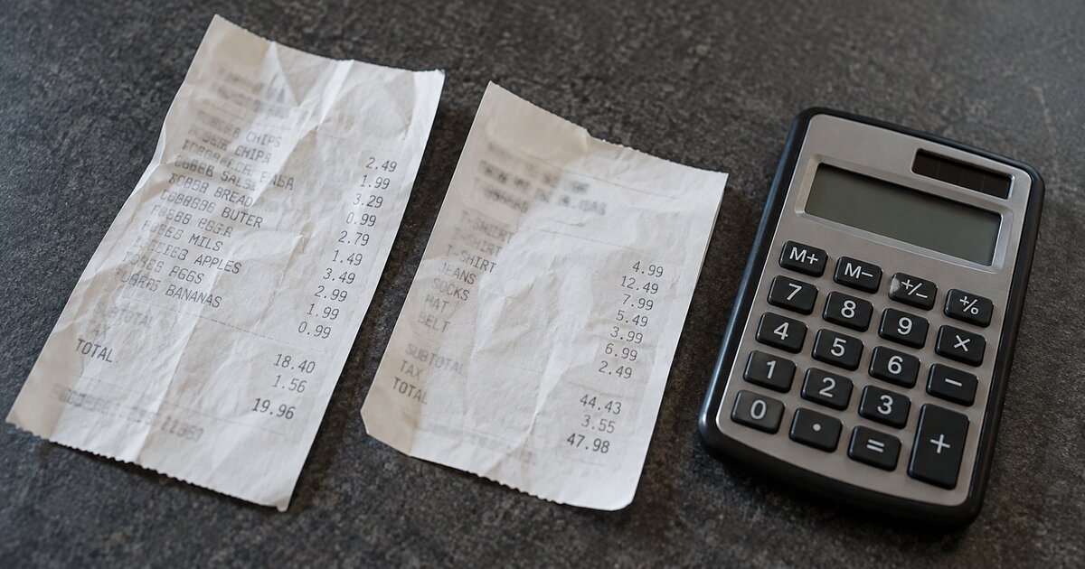 Two shopping receipts beside a calculator on a dark table.